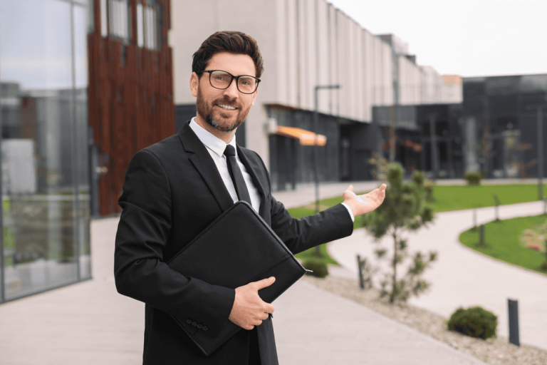 A man in a suit gestures toward a modern building, holding a black folder as if managing property line disputes, with a landscaped garden providing a serene backdrop.