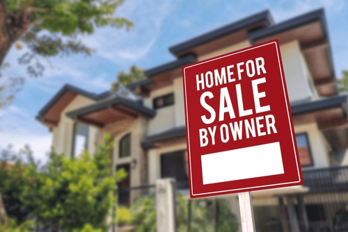 House with a "Home for Sale by Owner" sign in front, framed by the blurred backdrop of trees and sky—a serene setting that hints at tranquility, free from any property line disputes.