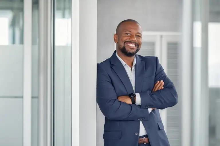 A man in a blue suit, exuding confidence and expertise, stands with arms crossed in a modern office setting, ready to navigate any property line disputes that come his way.