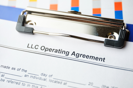 Close-up of an LLC Operating Agreement document on a clipboard, partially obscured by a colorful file folder, with text visible at the top—much like how unresolved property line disputes might overshadow critical business operations.