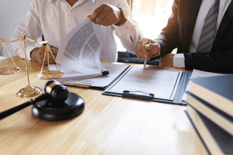 Two people are reviewing legal documents at a table adorned with scales, a gavel, and books, diligently navigating the complexities of property line disputes.