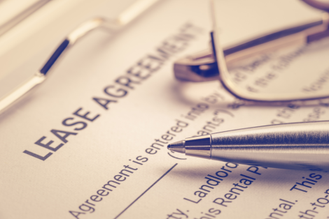 Close-up of a lease agreement document with a silver pen and reading glasses placed on top, symbolizing clarity in resolving property line disputes.