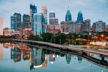 Philadelphia skyline at dusk is beautifully reflected in the Schuylkill River, with illuminated skyscrapers piercing a partly cloudy sky—a scene where city borders are clear, unlike property line disputes.