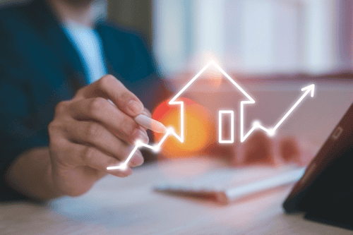 A person holds a pen pointing at a digital overlay featuring a rising arrow and house symbol, subtly hinting at the resolution of property line disputes and marking growth in the real estate market.