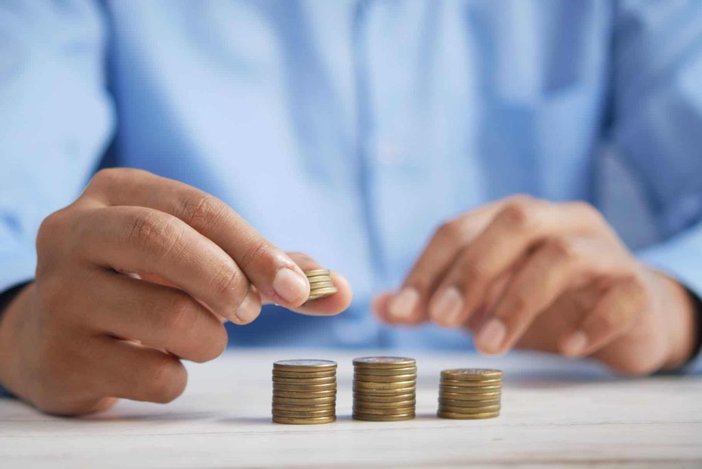 Person stacking coins on a table, wearing a blue shirt.