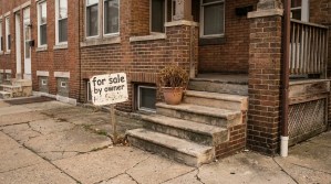 handwritten for sale by owner sign posted outside brick residential property